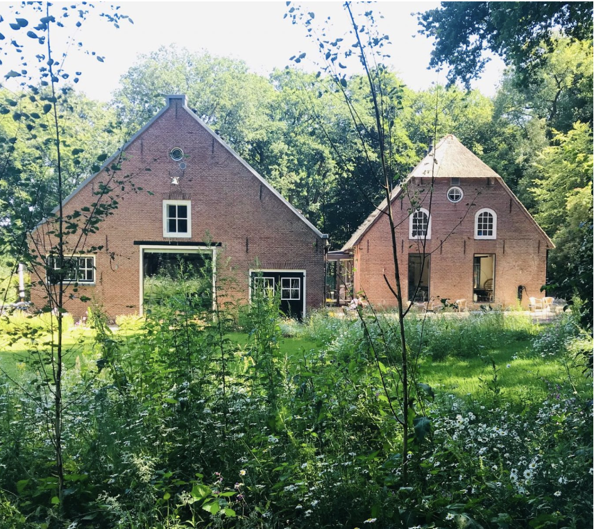 Landgoed met rode boerderijgebouwen tussen groen